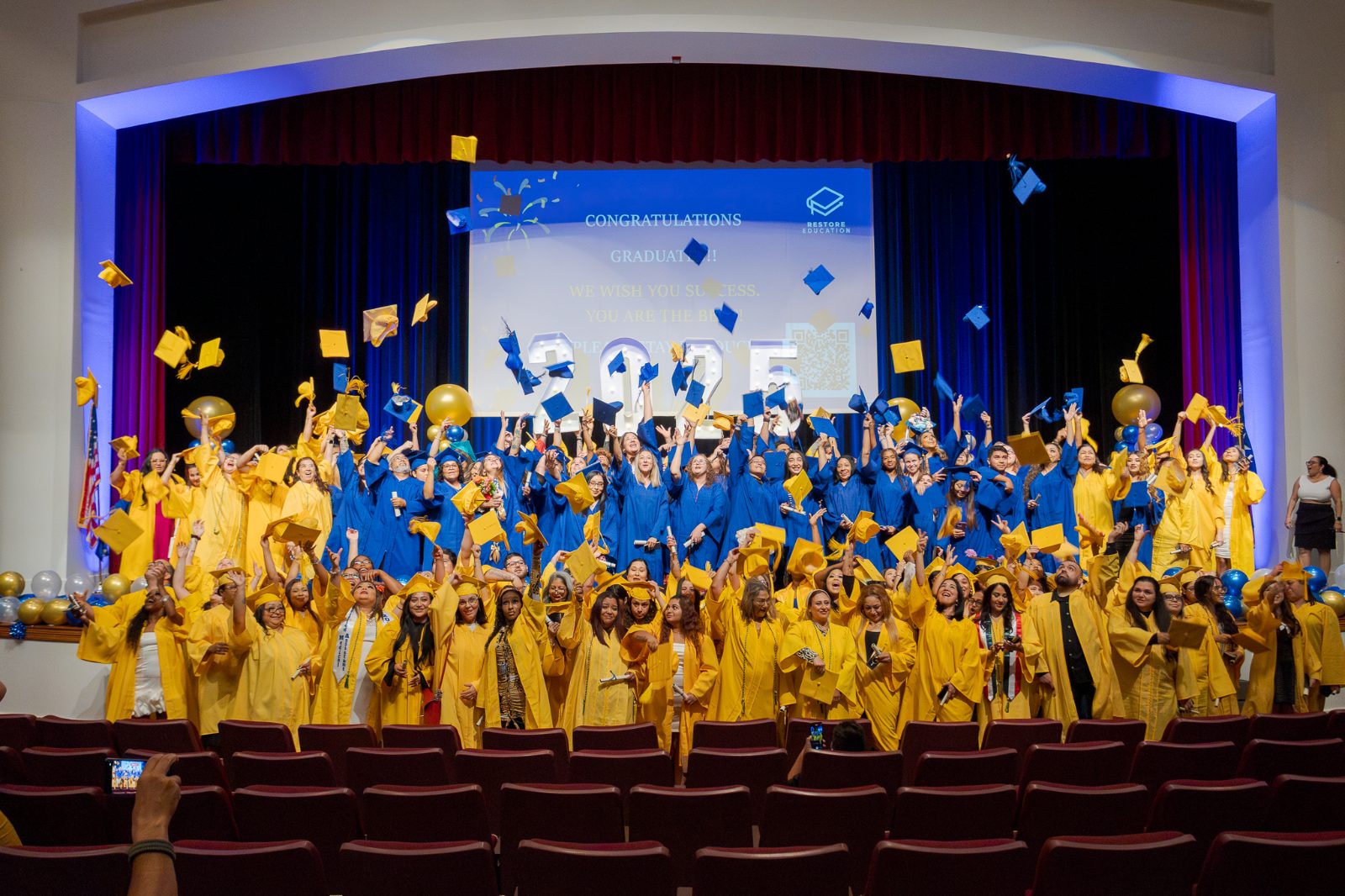 Graduates throwing their caps at the Restore Education commencement